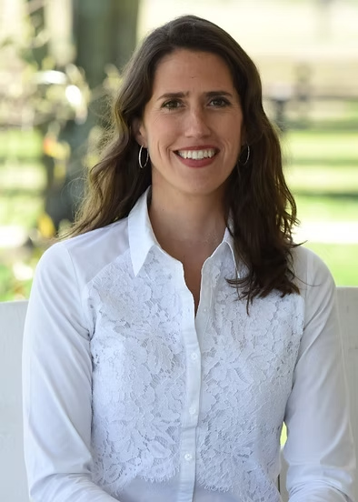 Woman with dark hair wearing white blouse with lace