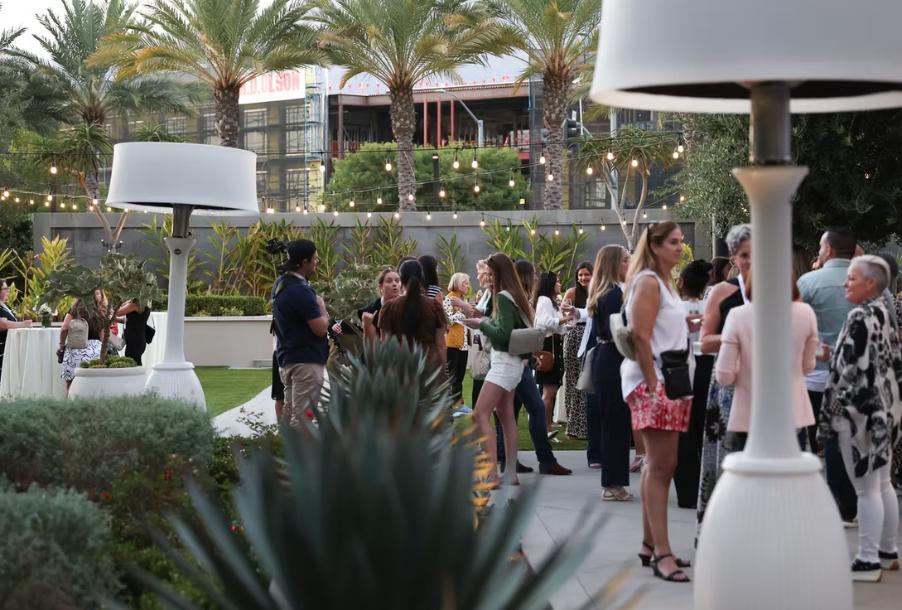 People standing talking on patio with plants and hanging lights
