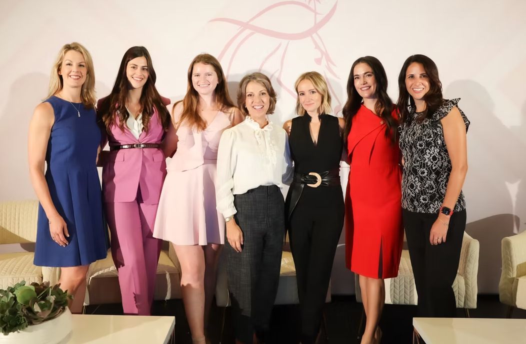 Women standing in room with logo on wall